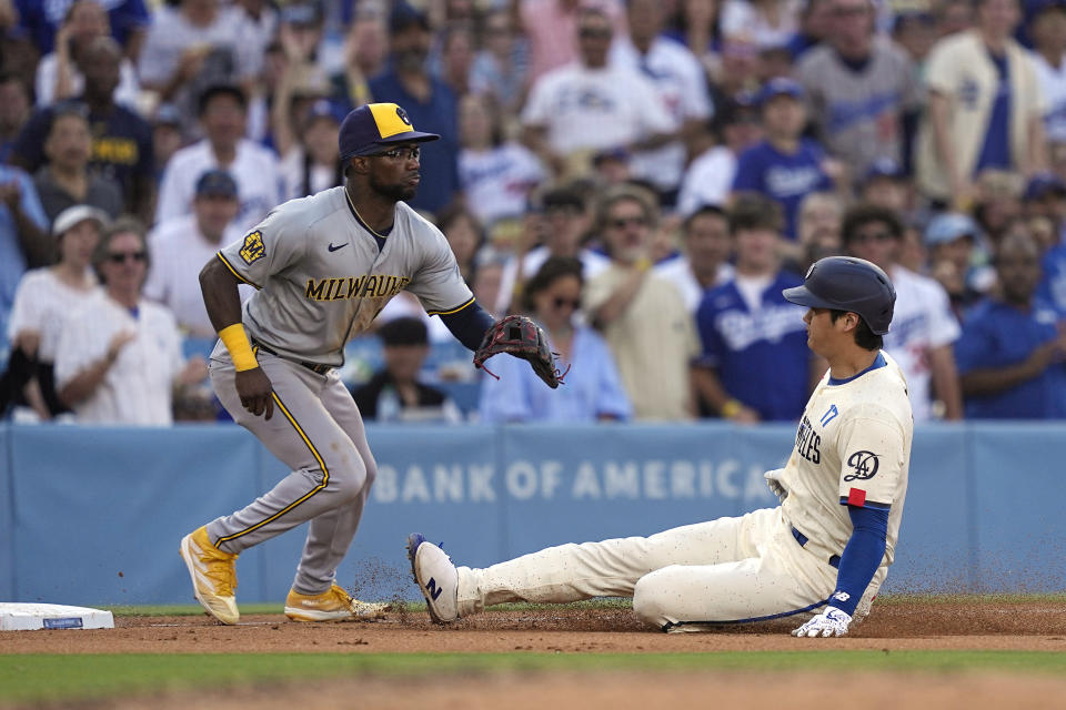 Los Angeles Dodgers' Shohei Ohtani, right, slides in for a triple as Milwaukee Brewers third baseman Andruw Monasterio waits for the ball during the sixth inning of a baseball game Saturday, July 6, 2024, in Los Angeles. (AP Photo/Mark J. Terrill)