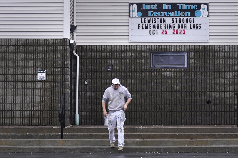 A painter passes a "Lewiston Strong!" sign displayed outside the Just-In-Time bowling alley, one of the sites of the Lewiston shootings, while taking a break from renovating following the incident, Wednesday, Dec. 27, 2023, in Lewiston, Maine. Immediately after Maine's deadliest mass shooting, the owners of the bowling alley and the bar in Lewiston where the gunman killed a total of 18 people were certain their doors were closed for good. But as time passed following the Oct. 25 shooting, they came to the same conclusion: They had to reopen. (AP Photo/Charles Krupa)