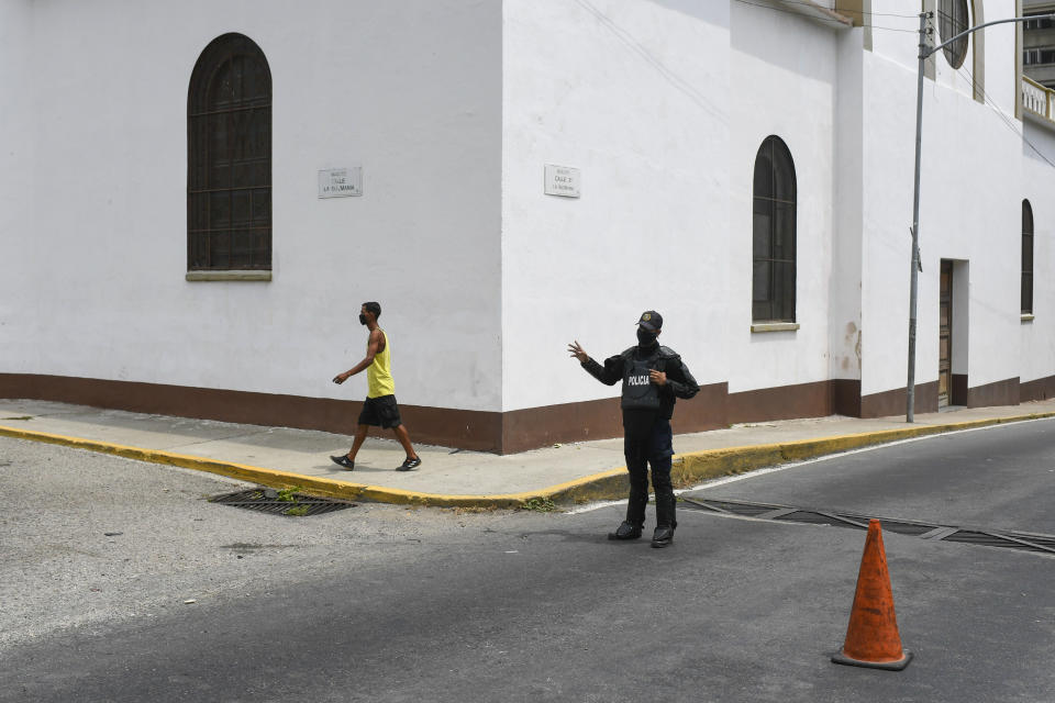 A police officer blocks a street in the Macuto area in La Guiara, Venezuela, Sunday, May 3, 2020. Interior Nestor Reverol said on state television that Venezuelan forces overcame an armed maritime incursion by boats from neighboring Colombia before dawn Sunday, in which several attackers were killed and others detained. (AP Photo/Matias Delacroix)