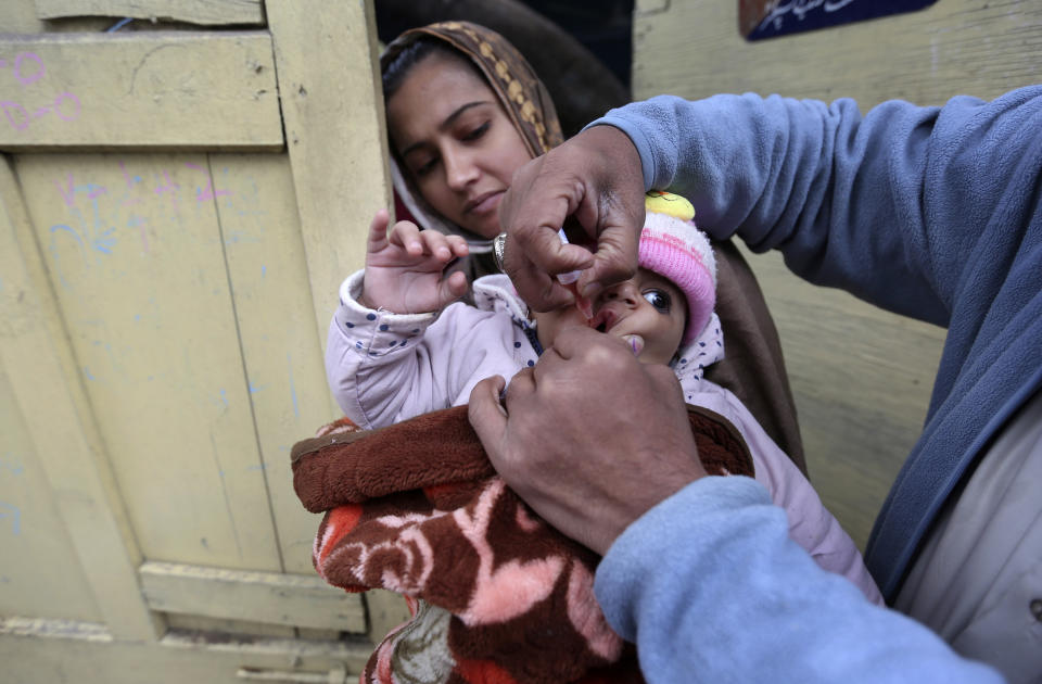 A health worker administers a polio vaccine to a child in Lahore, Pakistan, Monday, Jan. 24, 2022. Pakistani authorities on Monday launched this year's first nationwide anti-polio campaign despite facing a sudden surge of coronavirus cases in an effort aimed eradicating the crippling children's disease. (AP Photo/K.M. Chaudhry)