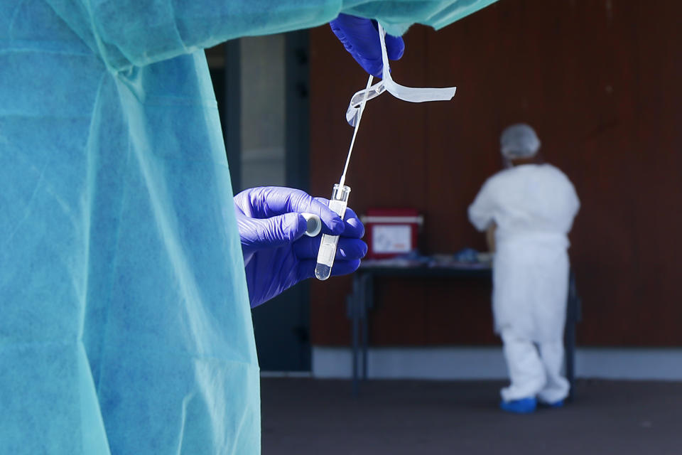 A technician holds a nasal swab sample for COVID-19 at a drive-through testing centre in Wambrechies, northern France, Monday, Sept.21, 2020. Coronavirus infections tipped the scales again in France on Saturday with nearly 13,500 new infections in 24 hours. (AP Photo/Michel Spingler)