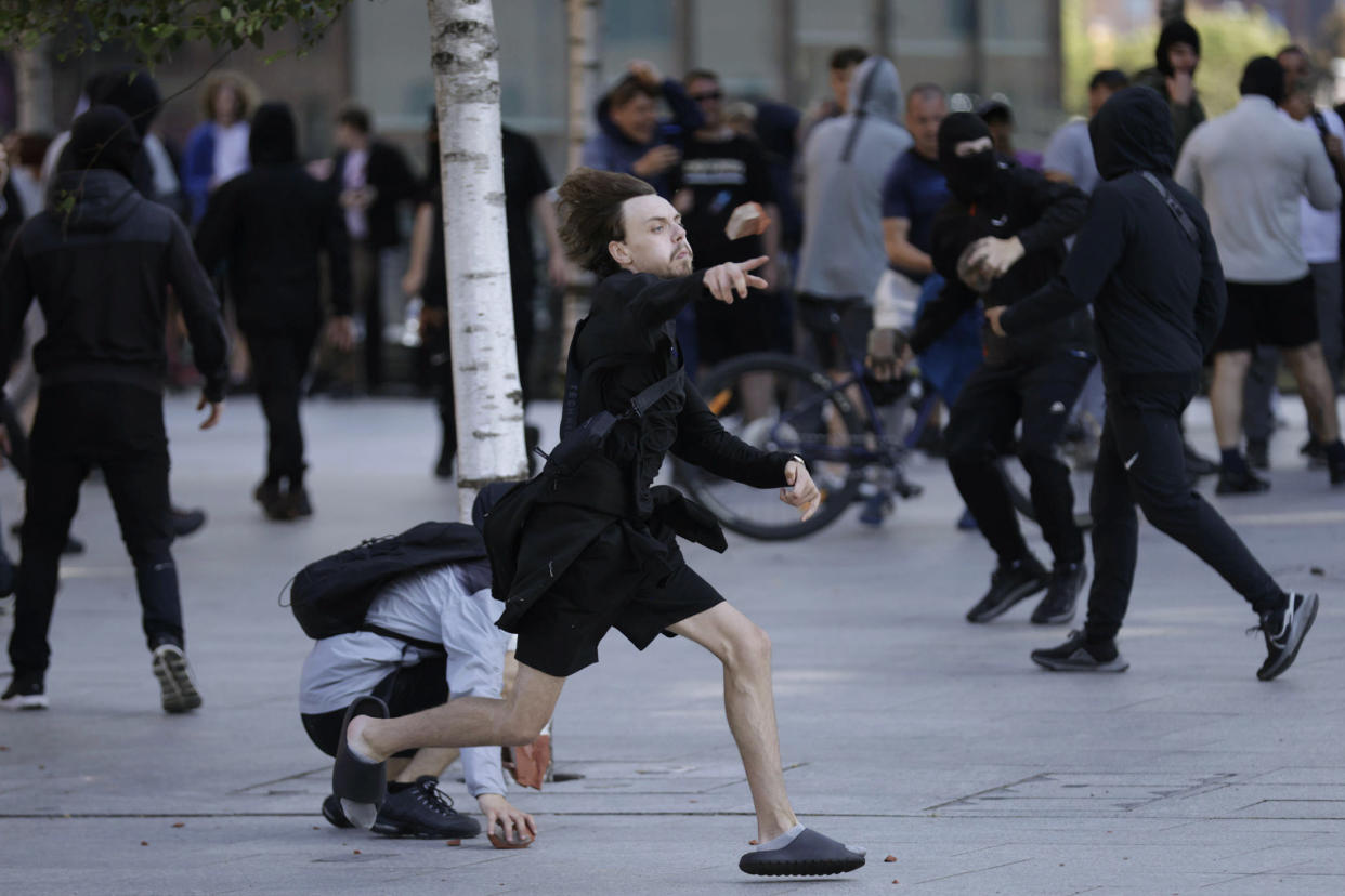 A demonstrator throws a brick during a protest in Liverpool, England