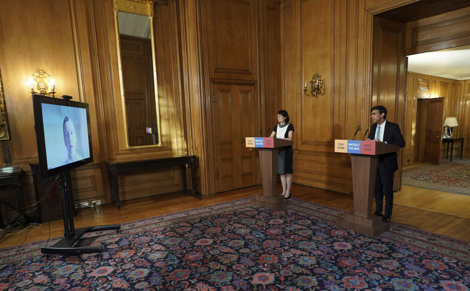 In this image made available by British government because no media allowed into 10 Downing Street because of the coronavirus pandemic, showing Chancellor of the Exchequer Rishi Sunak, right, holding a digital press conference about the COVID-19 coronavirus, with Deputy Chief Medical Officer Doctor Jenny Harries, centre, inside 10 Downing Street, London, Thursday March 26, 2020. Sunak on Thursday announced measures to give financial help to self-employed people. (Pippa Fowles/10 Downing Street via AP)