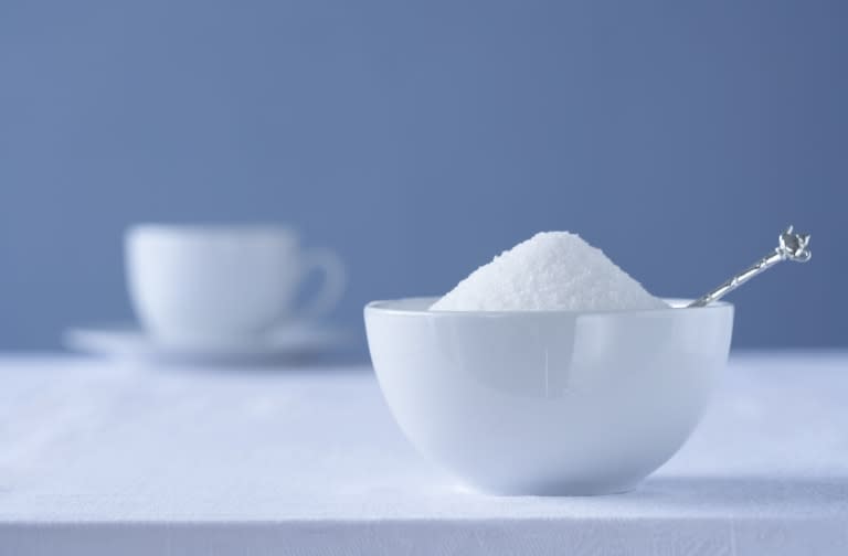Bowl of sugar on table, tea cup in background