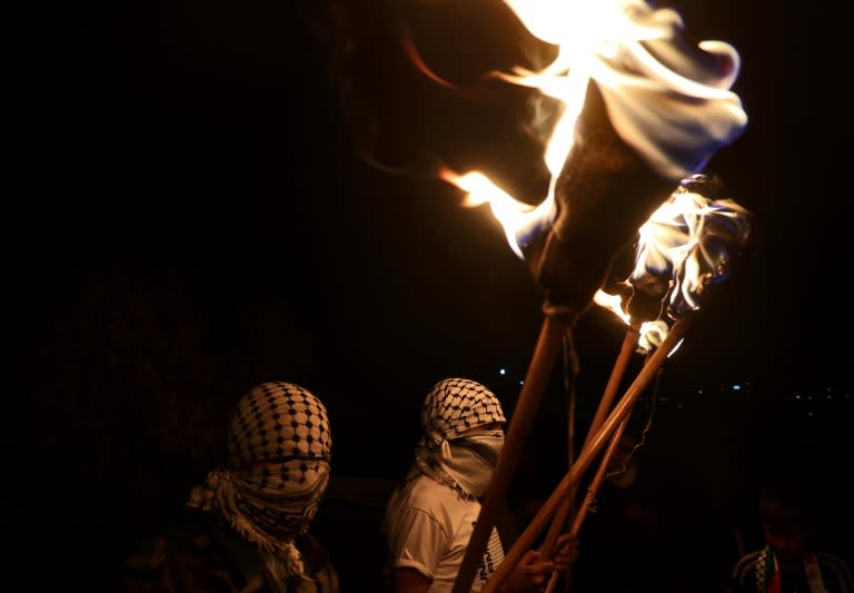 Palestinian protesters hold torches during a demonstration against the Israeli settler outpost of Eviatar on June 28, 2021