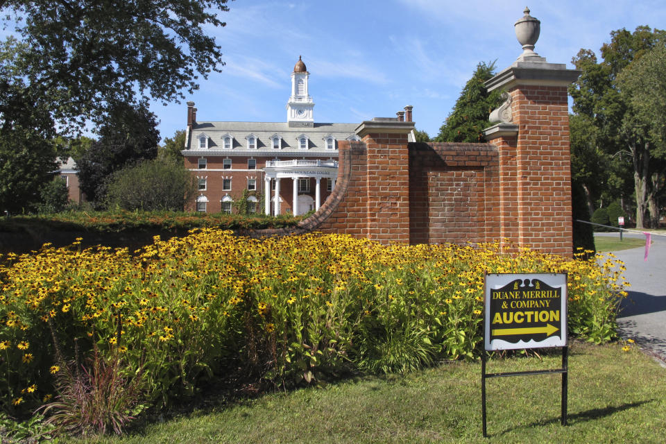 In this Friday, Sept. 20, 2019 photograph, a sign points to an auction at Green Mountain College in Poultney, Vt. The school closed in May and now its hometown is awaiting to hear what will become of the campus. (AP Photo/Lisa Rathke)