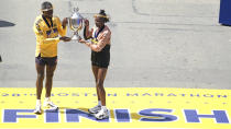 Boston Marathon men's division winner Sisay Lemma, of Ethiopia, left, and women's division winner Hellen Obiri, of Kenya hold up the trophy at the Boston Marathon, Monday, April 15, 2024, in Boston. (AP Photo/Charles Krupa)