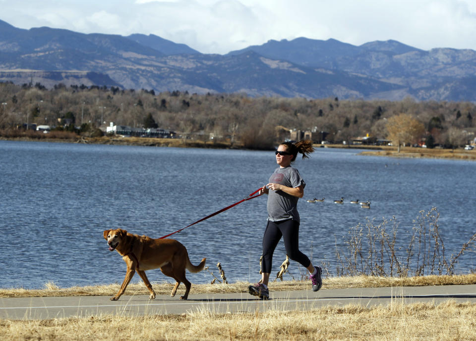 This photo taken on Dec. 7, 2012 shows Rachel Gardner jogging with her dog Allie at Sloan's Lake in Denver. Get a panoramic view of the mountains and a good hike without leaving the Denver sunbelt at this 177-acre lake on the far western edge of Denver. (AP Photo/Ed Andrieski)