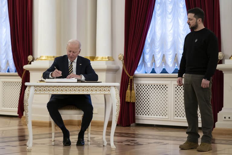 El presidente ucraniano Volodymyr Zelenskyy observa mientras el mandatario estadounidense Joe Biden firma el libro de visitantes en el Palacio Mariinsky, en Kiev, el lunes 20 de febrero de 2023. (AP Foto/Evan Vucci, Pool)