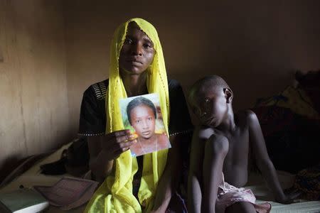 Rachel Daniel, 35, holds up a picture of her abducted daughter Rose Daniel, 17, as her son Bukar, 7, sits beside her at her home in Maiduguri in this May 21, 2014 file photo. REUTERS/Joe Penney/Files