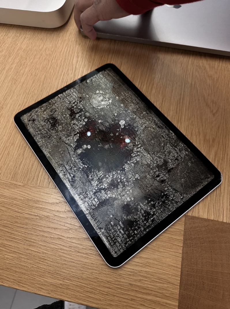 A cracked tablet screen with a heart-like pattern and two glowing spots resembling eyes