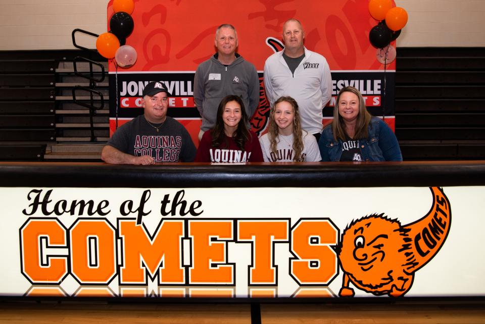 Julie Mach, joined by her former coach Tom Dunn, future coach Brian Morris and her family, signs with the Aquinas women's basketball team.