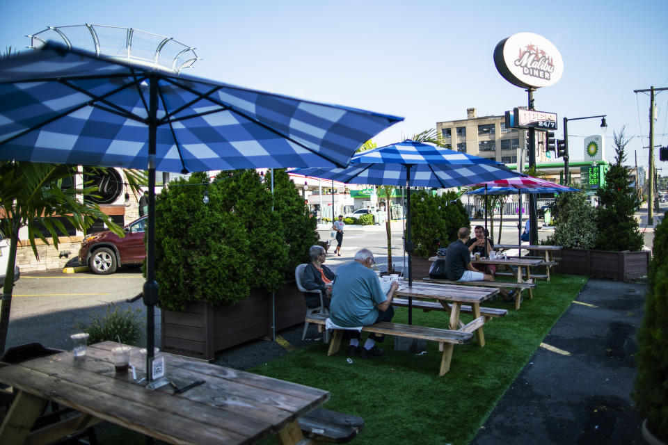 People wait for their food as they eat outside of a local diner on Friday, Sept. 4, 2020, in Hoboken, N.J. Tape measures will join tapas as social distancing becomes essential to the ambiance at New Jersey restaurants preparing for the limited resumption Friday of indoor dining. Gov. Phil Murphy gave the go-ahead on Monday for indoor dining not to exceed 25% of capacity. (AP Photo/Eduardo Munoz Alvarez)