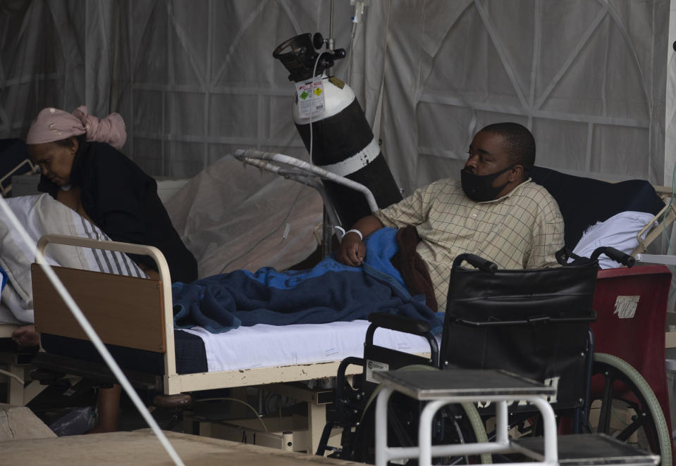 A patient lays in his bed at the Steve Biko Academic Hospital's outside parking area in Pretoria, South Africa, Monday, Jan. 11, 2021. As the numbers of new confirmed cases rise, South Africa's hospitals are exceeding capacity, according to health officials. (AP Photo/Denis Farrell)