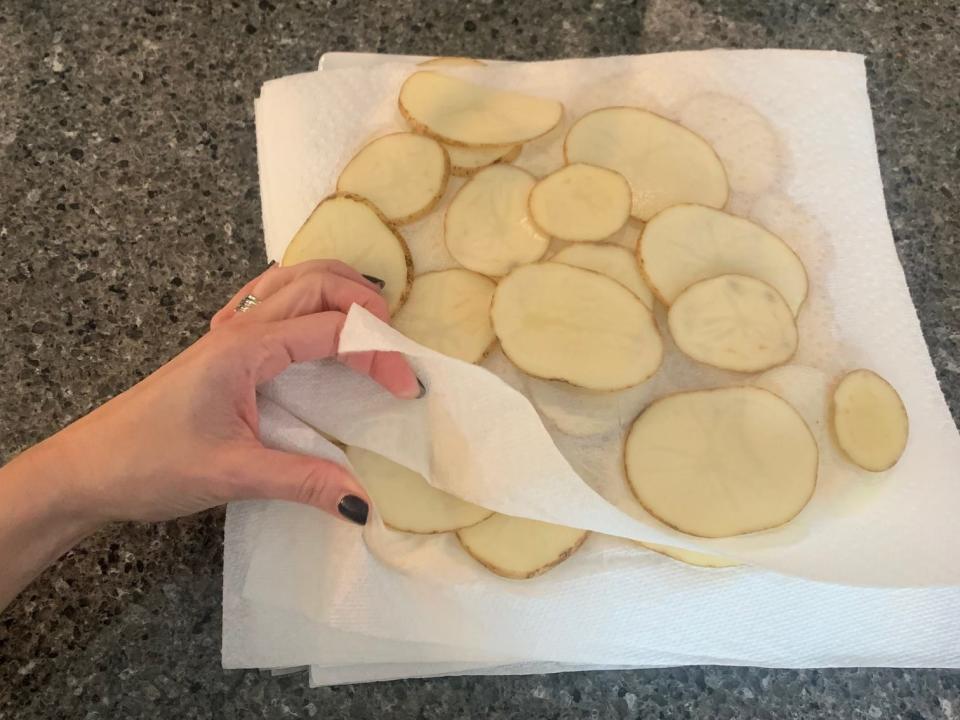 potato slices in between layers of paper towels on a kitchen counter