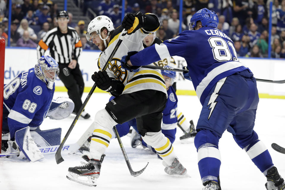 Boston Bruins right wing David Pastrnak (88) gets cross-checked by Tampa Bay Lightning defenseman Erik Cernak (81) as he chases a bouncing puck in front of Lightning goaltender Andrei Vasilevskiy (88) during the third period of an NHL hockey game Thursday, Dec. 12, 2019, in Tampa, Fla. (AP Photo/Chris O'Meara)