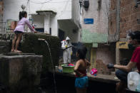 Children watch as Jorge Alexandre sprays disinfectant near a community water spring to avoid the spread of the new coronavirus in the Santa Marta slum of Rio de Janeiro, Brazil, Friday, April 10, 2020. The virus initially brought to the region largely by wealthy citizens or visitors coming from Europe and the United States is now increasingly concentrated in poorer neighborhoods where residents have few means of protecting themselves. (AP Photo/Leo Correa)