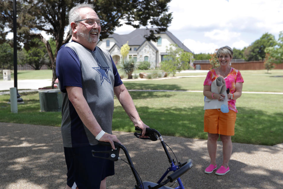 Stephen Donelson, left, smiles as he walks up his driveway to his home accompanied by his wife, Terri, in Midlothian, Texas on Friday, June 19, 2020, after his 90-day stay in the Zale Hospital on the UT Southwestern Campus. Donelson’s family hadn’t left the house in two weeks after COVID-19 started spreading in Texas, hoping to shield the organ transplant recipient. Yet one night, his wife found him barely breathing, his skin turning blue, and called 911. (AP Photo/Tony Gutierrez)