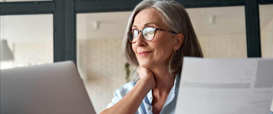 Smiling mature middle aged business woman using laptop