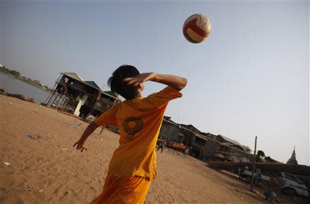 A Vietnamese boy plays volleyball with his friend near their house on the banks of the Mekong river in Phnom Penh March 11, 2014. REUTERS/Samrang Pring