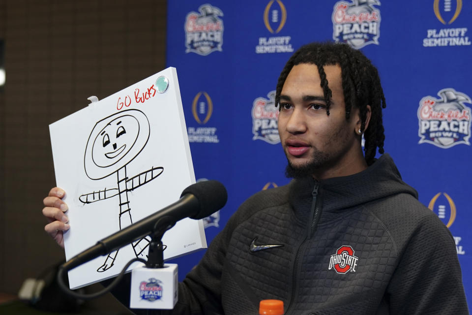 Ohio State quarterback C.J. Stroud (7) holds up his drawing of Ohio State mascot Brutus during media day for the Peach Bowl NCAA college football game against Georgia Thursday, Dec. 29, 2022, in Atlanta. (AP Photo/John Bazemore)