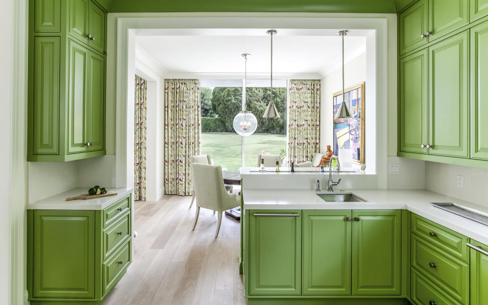 This image released by Tom Stringer Design Partners shows a kitchen in Palm Springs, Calif., with cabinetry painted in Benjamin Moore’s Kiwi paint color. The vivid green is picked up elsewhere in the home via artwork, accessories and textiles. (Jorge Gera/Tom Stringer Design Partners via AP)
