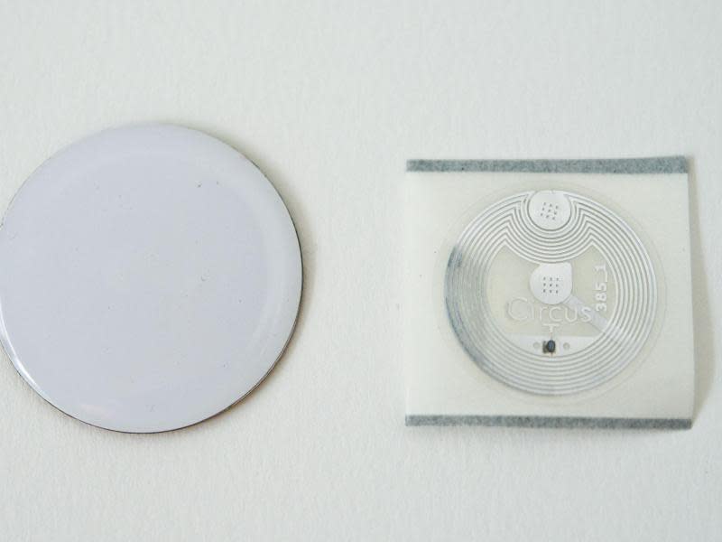 NFC-Chips sind nichts anderes als eine hauchdünne Spule, hier in einem transparenten Sticker (r) und einem Aufkleber (l) verarbeitet. Foto: Inga Kjer