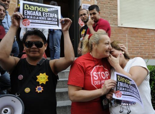 Esther Sanz (centre) comforts Luz Maria Reyes Coral on Wednesday before an attempted mortgage foreclosure on Reyes Coral's house in Madrid. Spain's government this month instructed banks to set aside 30 bn euros in 2012 in case property-related loans go bad