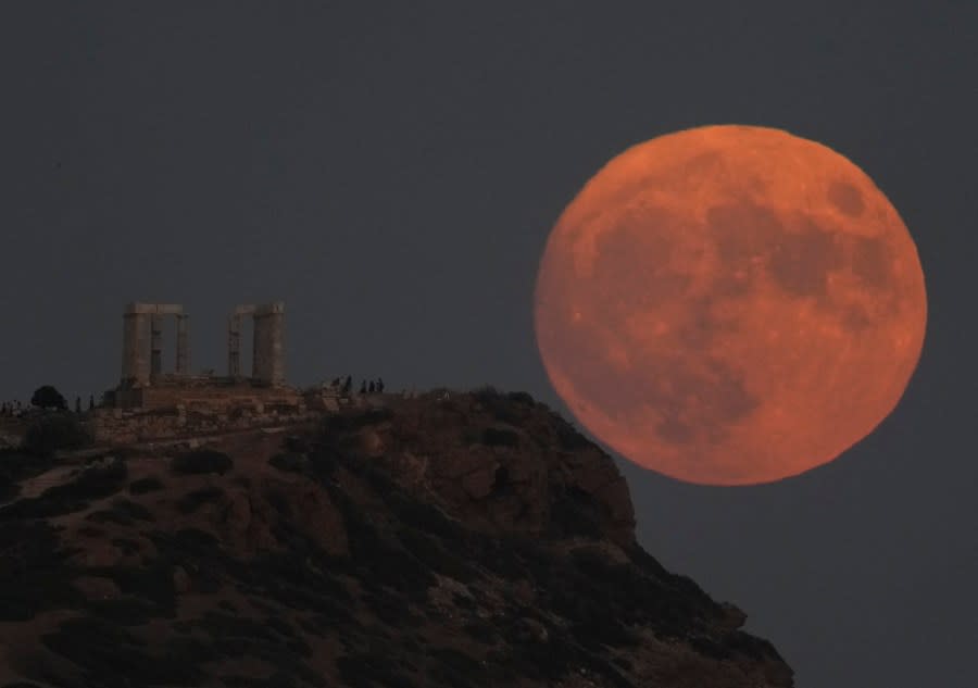 The supermoon rises behind the ancient temple of Poseidon at Cape Sounion, about 70 kilometers (45 miles) south of Athens, Greece, Wednesday, Aug. 30, 2023. The cosmic curtain rose Wednesday night with the second full moon of the month, the reason it is considered blue. It’s dubbed a supermoon because it’s closer to Earth than usual, appearing especially big and bright. (AP Photo/Thanassis Stavrakis)