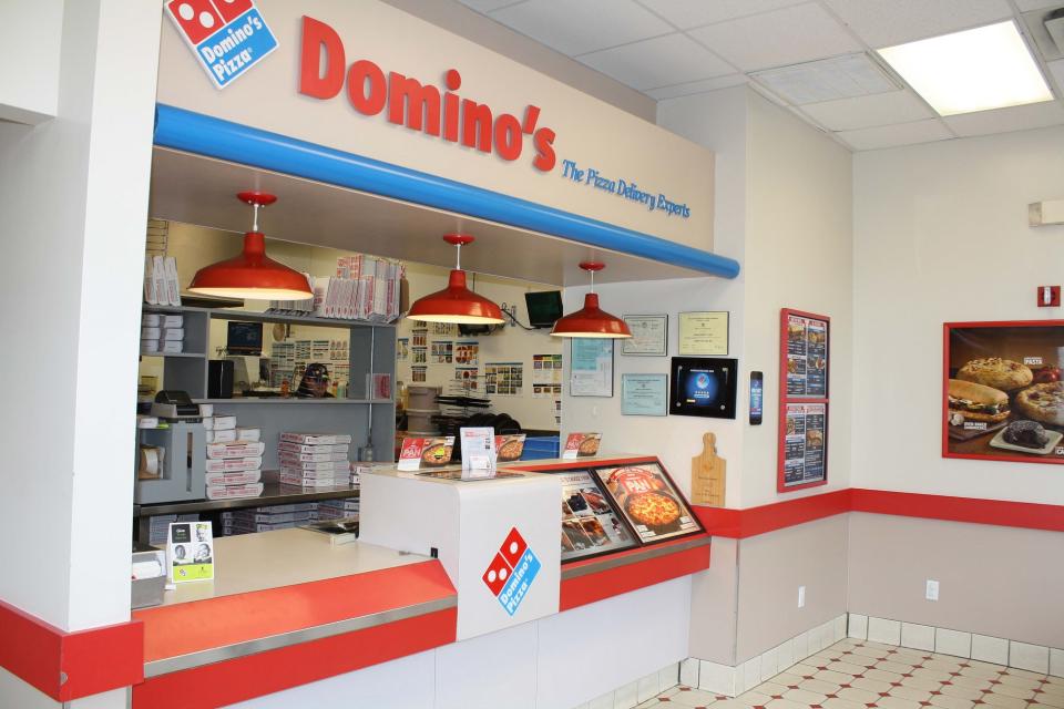 Inside of Domino's store with counter, heat lamps, logo, and display materials.