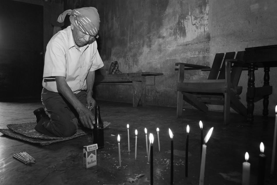 <p>Shaman Antonio Mendoza prepares a ceremonial offering. (Photograph by Fran Antmann) </p>