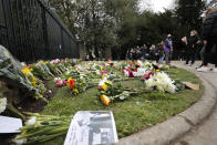 People look at flowers and other items left outside the gates of Windsor Castle, a day after the death of Britain's Prince Philip, in Windsor, England, Saturday, April 10, 2021. Britain's Prince Philip, the irascible and tough-minded husband of Queen Elizabeth II who spent more than seven decades supporting his wife in a role that mostly defined his life, died on Friday. (AP Photo/Frank Augstein)