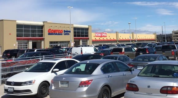 The exterior of a Costco with a crowded parking lot.