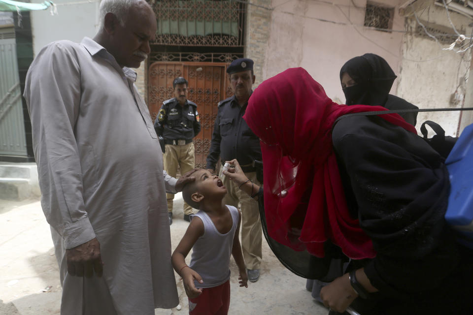 Policemen provide security for a health worker administering a polio vaccine to a child in Karachi, Pakistan, Monday, May 23, 2022. Pakistan launched a new anti-polio drive on Monday, more than a week after officials detected the third case so far this year in the country's northwestern region bordering Afghanistan. (AP Photo/Fareed Khan)