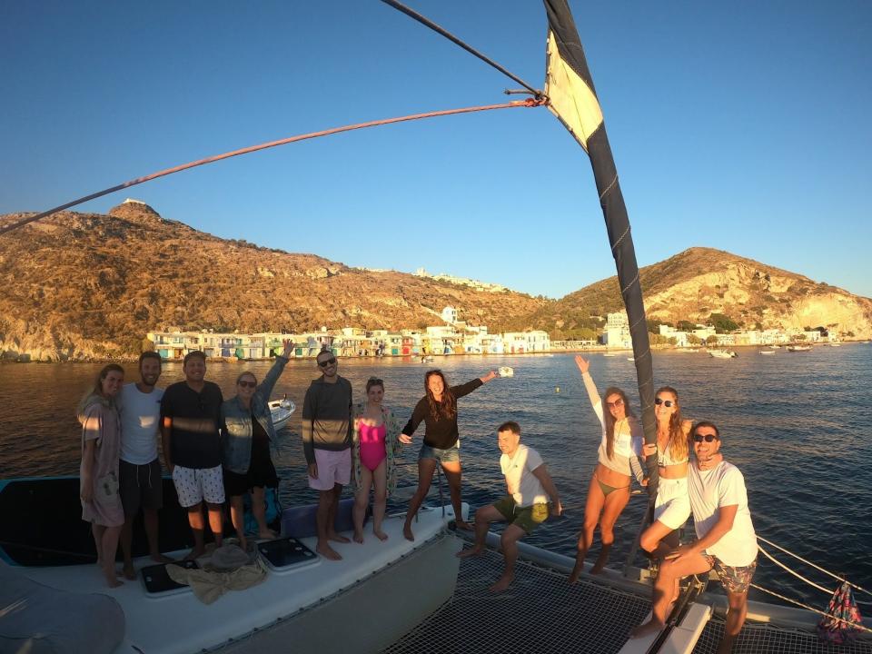 People on a boat in greece with a coast in the background and blue skies