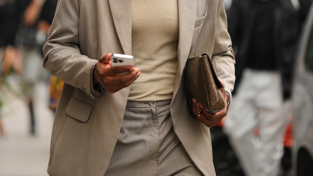 a man wearing sunglasses and a brown jacket holding a cell phone