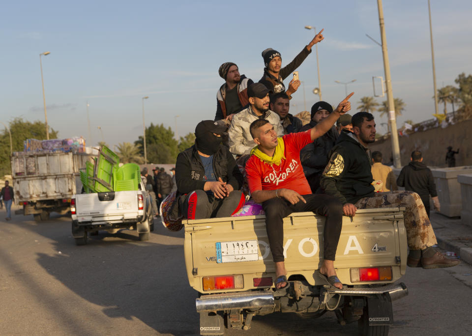 Pro-Iranian militiamen and their supporters board trucks loaded with items from a sit-in while driving away from the U.S. Embassy, in Baghdad, Iraq, Wednesday, Jan. 1, 2020. U.S. troops fired tear gas on Wednesday to disperse pro-Iran protesters who were gathered outside the U.S. Embassy compound in Baghdad for a second day. (AP Photo/Nasser Nasser)