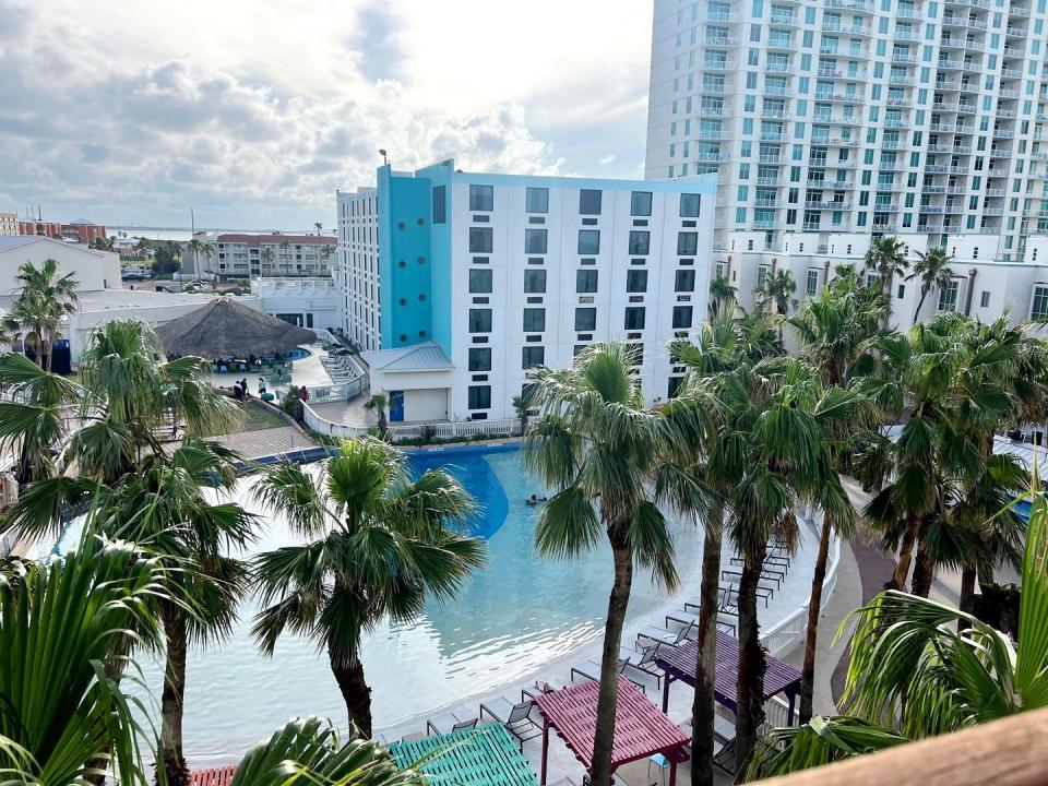 pool surrounded by chairs, cabanas, palm trees and a tiki hut bar