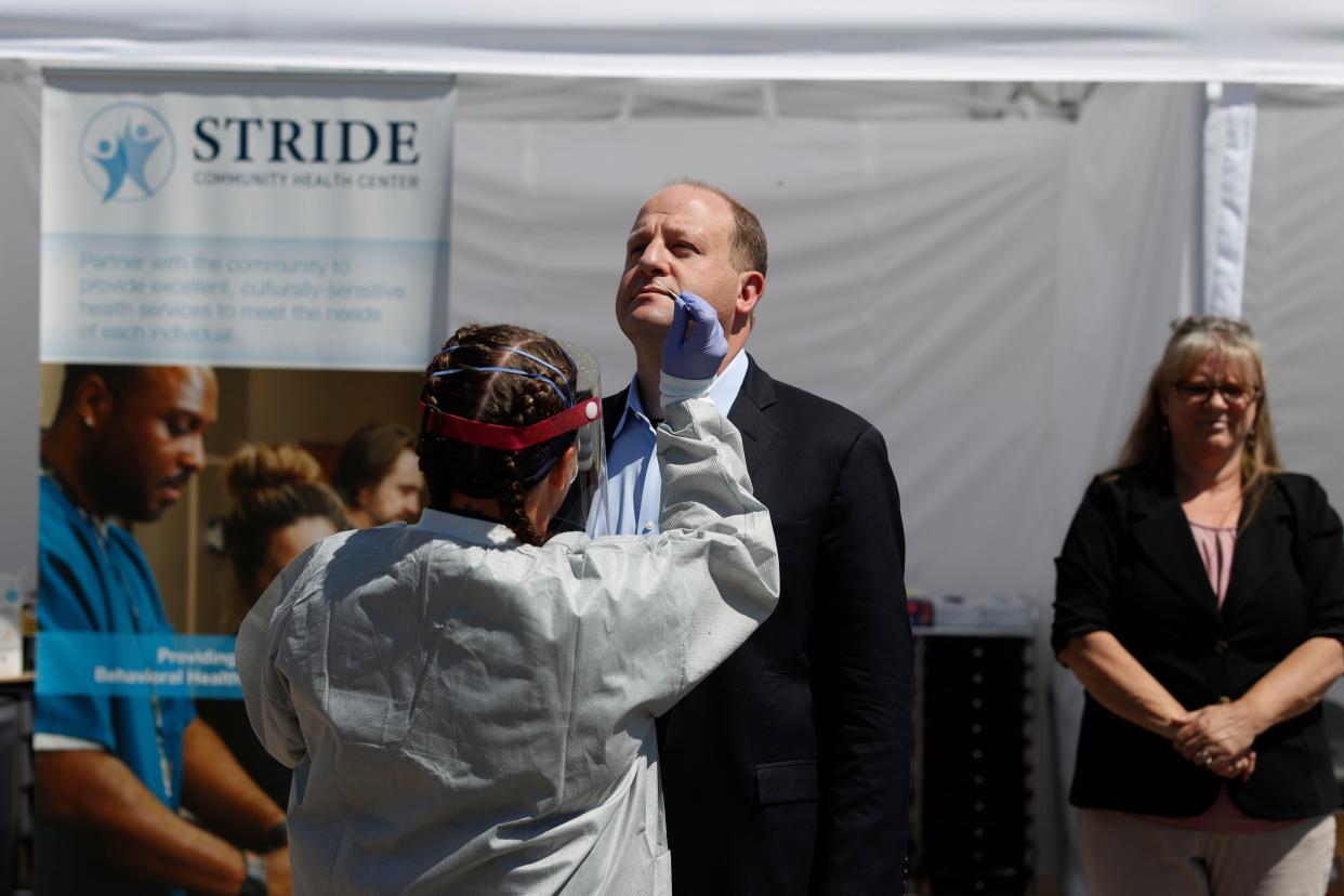 Colorado Governor Jared Polis is administered a nasal test for the new coronavirus during a news conference outside the Stride Community Health Center Monday, May 18, 2020, in Wheat Ridge, Colo.