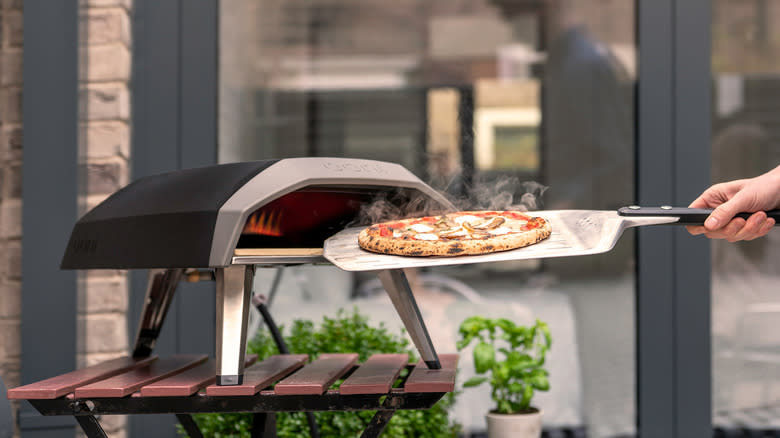 Person using pizza oven outside 