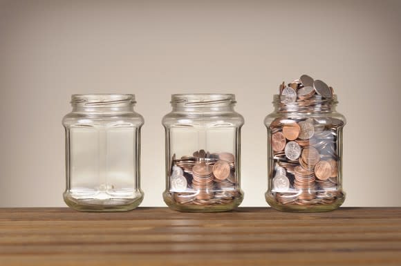 Empty jar, half-full jar of coins, and overflowing jar of coins.