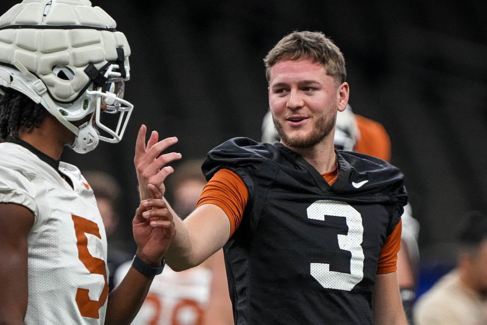 Texas quarterback Quinn Ewers, right, talks to wide receiver Adonai Mitchell during practice at the Superdome in New Orleans on Saturday. Ewers and the Longhorns will take on the Washington Huskies in a College Football Playoff semifinal Monday at 7:45 p.m.