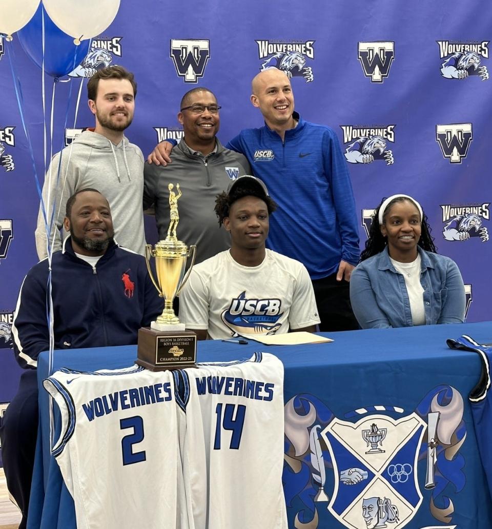 Alfonzo Ross of Woodville-Tompkins with his parents and coaches as he signed to play college basketball at USC Beaufort on Wednesday.