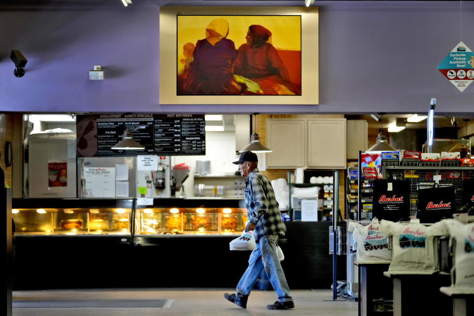 A man walks beneath traditional Navajo artwork inside the local grocery store, Monday, March 4, 2024, in Tuba City, Ariz. The grocery store sits along a stretch of highway that is the de facto border between the Navajo and Hopi Indian reservations and two time zones. Mind-bending time calculations is what people in the largest Native American reservation in the U.S. have to endure every March through November. (AP Photo/Matt York)