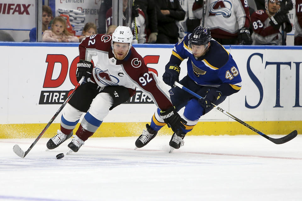 Colorado Avalanche's Gabriel Landeskog (92), of Sweden, controls the puck in front of St. Louis Blues' Ivan Barbashev (49), of Russia, during the first period of an NHL hockey game Monday, Oct. 21, 2019, in St. Louis. (AP Photo/Scott Kane)