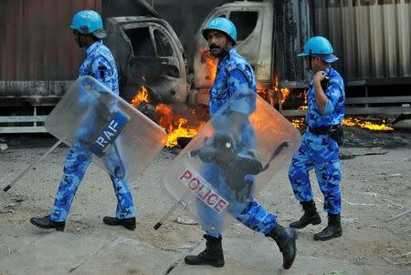 Members of the security forces make their way past burning lorries in Bengaluru, which were set on fire by protesters after Supreme Court ordered Karnataka to release 12,000 cubic feet of water per second every day from the Cauvery river to neighbouring Tamil Nadu, India September 12, 2016. REUTERS/Abhishek N. Chinnappa