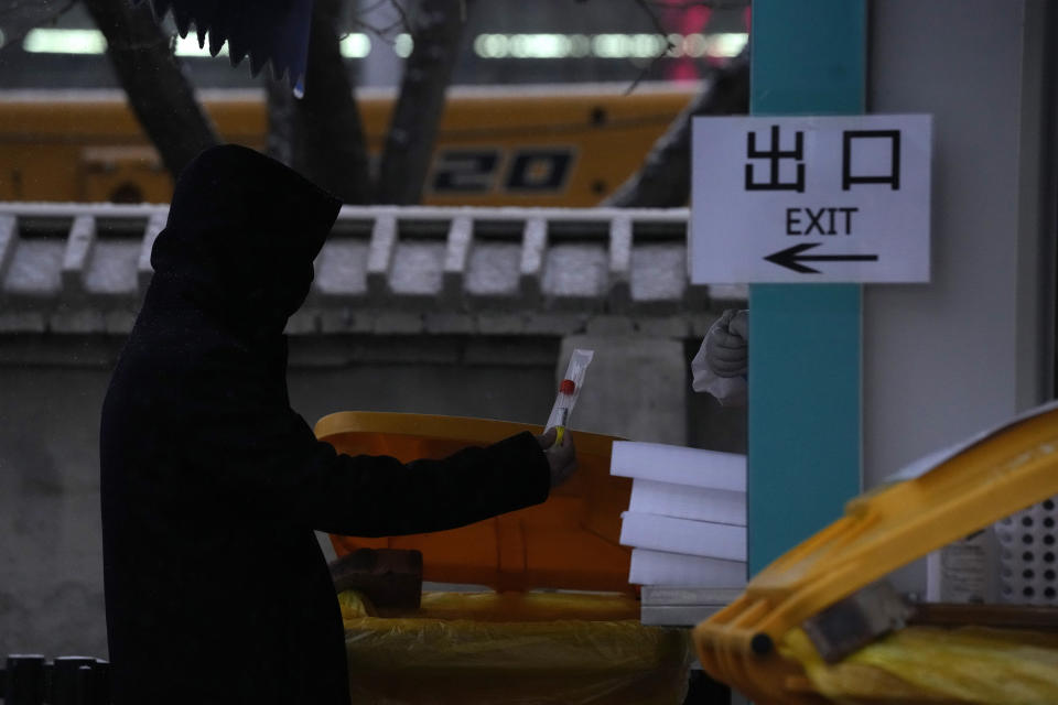 A resident holds up a tube and swab to get tested at a nuclei test station in Beijing, China, Friday, Jan. 21, 2022. The sweeping "zero-tolerance" policies that China has employed to protect its people and economy from COVID-19 may, paradoxically, make it harder for the country to exit the pandemic. (AP Photo/Ng Han Guan)