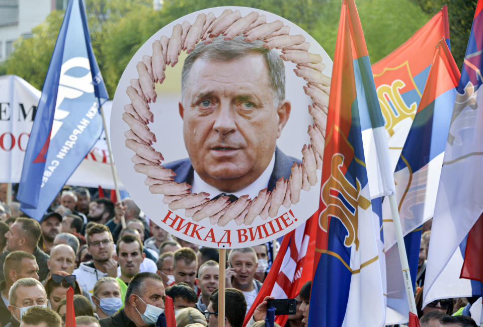 FILE- A person holds a banner showing the Bosnian Serb member of the tripartite Presidency of Bosnia Milorad Dodik that reads: "Never Again!", during a protest against the government in Banja Luka, in Serb-dominated part of Bosnia, on Oct. 2, 2021. Long-reigning Bosnian Serb leader, Milorad Dodik, has grown increasingly hostile this week as the West turned up the pressure on him to stop a spiraling secessionist campaign in his multiethnic Balkan country of 3.3 million people that has never truly recovered from its fratricidal 1992-95 war. (AP Photo/Radivoje Pavicic, File)