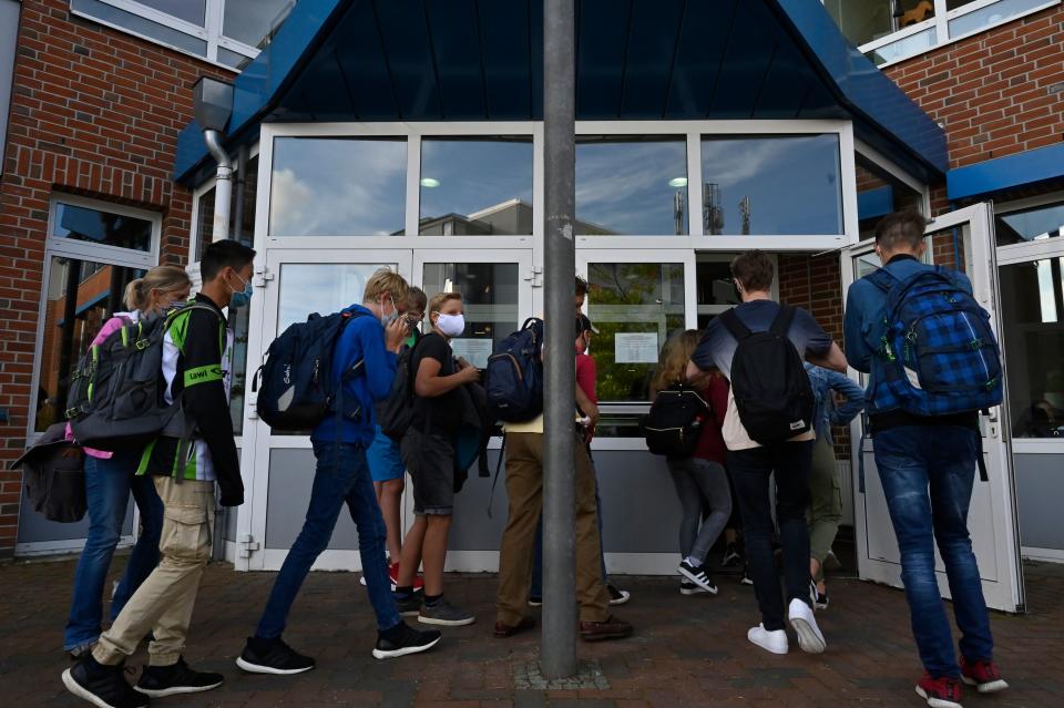Students put on their face covers as they head to class at the Christophorusschule school in Rostock, northern Germany, on August 3, 2020, as school resumed after the summer break in the German state of Mecklenburg-Vorpommern (Mecklenburg-Western Pomerania), amid a Coronavirus Covid-19 pandemic. (Photo by John MACDOUGALL / AFP) (Photo by JOHN MACDOUGALL/AFP via Getty Images)