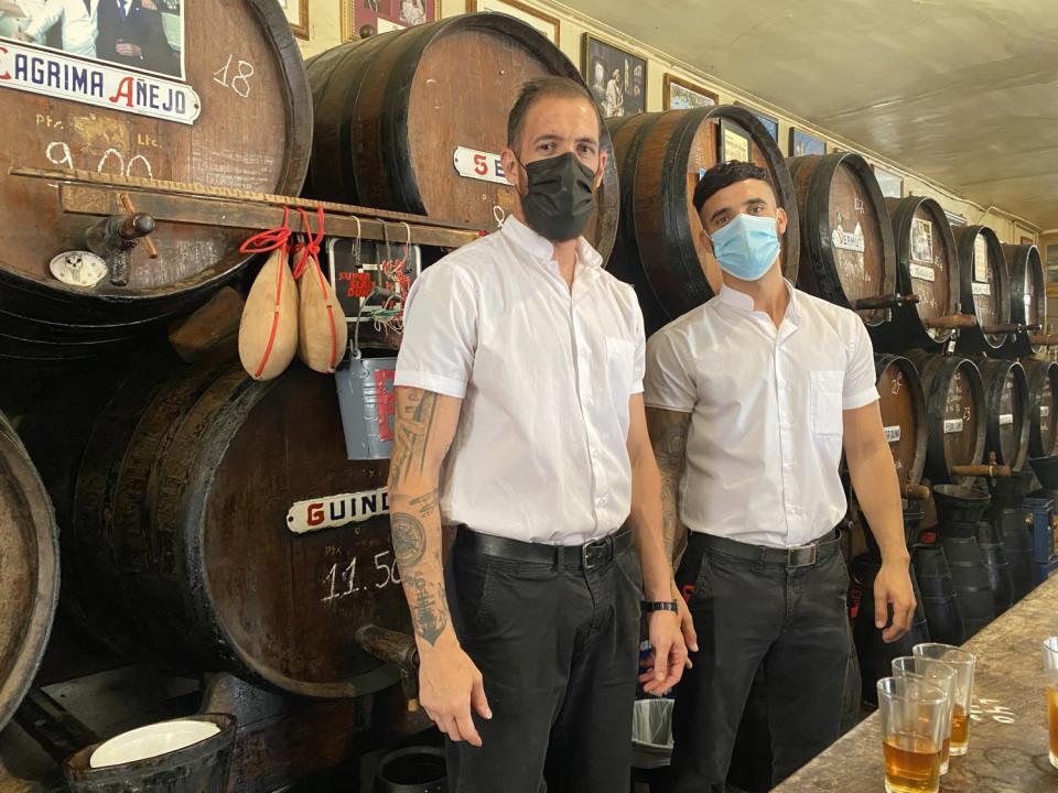 Servers stand next to wooden barrels at Antigua Casa de Guardia